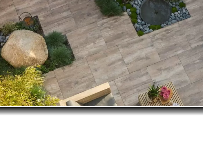 Tuin met een hond op kunstgras, een betonschutting en een houten tuinbank.